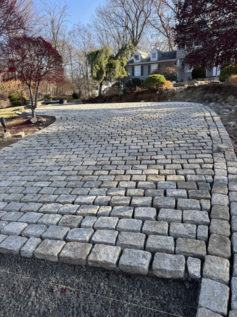 Cobblestone driveway paving project with curved driveway and stone border in Connecticut.