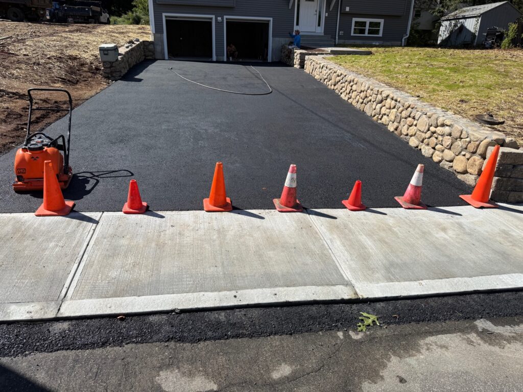 Newly paved asphalt driveway with stone retaining wall in Enfield Connecticut