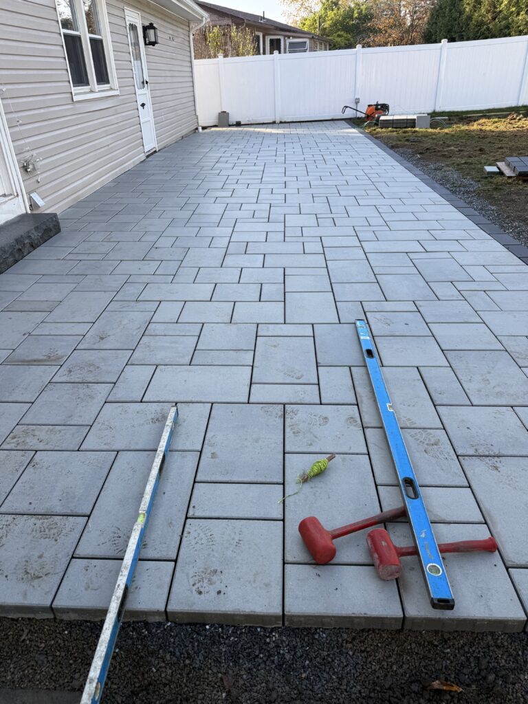 Paver patio under construction with tools along house in Hartford Connecticut